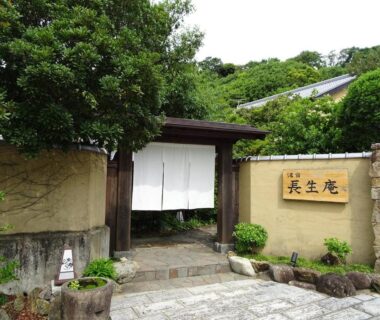 Stone path leading to wooden gate with white noren and Choseian signboard, Wakayama Kansai ryokan entrance