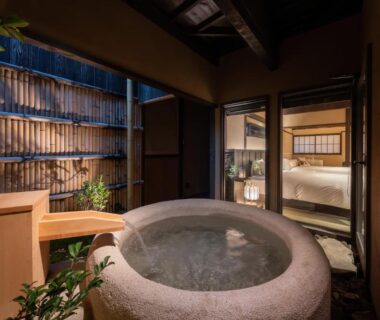 Outdoor stone bath in bamboo courtyard with shoji doors opening to tatami room at Nazuna Kyoto Higashi Honganji