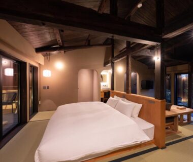 Tatami room with low bed, exposed wooden beams and sliding shoji doors at Nazuna Kyoto Higashi Honganji, Kyoto