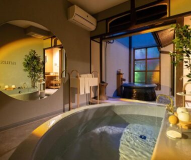 Warm-lit indoor baths with circular mirror and wooden tub at Nazuna Kyoto Nijo-jo Kyoto