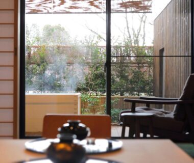 Tatami room with low table and shoji screens overlooking a garden and wooden outdoor bath