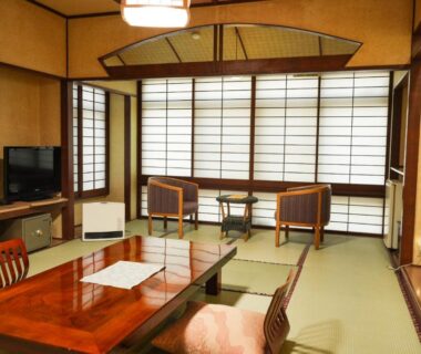 Tatami room with low wooden table, zabuton cushions, shoji screens and seating at New Ogiya, Fukushima