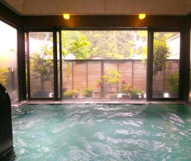 Indoor onsen bath with garden-facing glass windows at New Ogiya, Fukushima