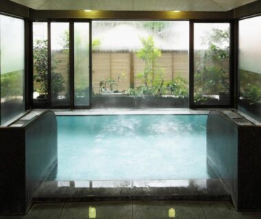 Steam rising from indoor onsen bath with garden view at New Ogiya Fukushima