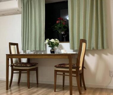 Wooden dining table with two chairs, flowers and green curtains in a Tokyo ryokan room