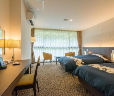 Twin beds with desk and seating area at New Welcity Yugawara, Shizuoka
