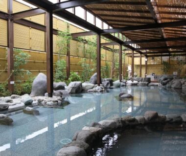 Covered stone onsen bath with rock accents and bamboo fencing at New Welcity Yugawara, Shizuoka, Chūbu