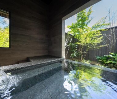 Stone soaking tub with wooden interior and small garden view at Nihon-no-Ashitaba, Ōita