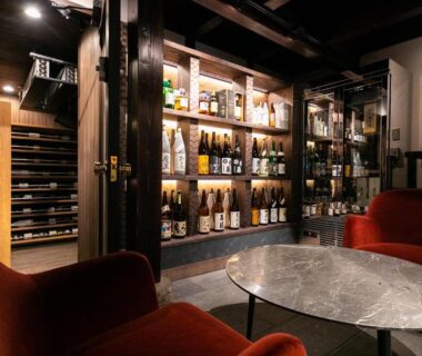 Plush red lounge chairs and marble table beside bottled display at Nihon-no-Ashitaba in Ōita, Kyūshū