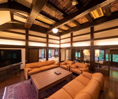 Spacious wooden communal lounge with sofas and exposed beams at Nihon-no-Ashitaba, Ōita, Kyūshū
