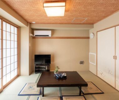Tatami room with low table, shoji screens and flat-screen TV at Nihonbashi Kakigara Ryokan Tokyo