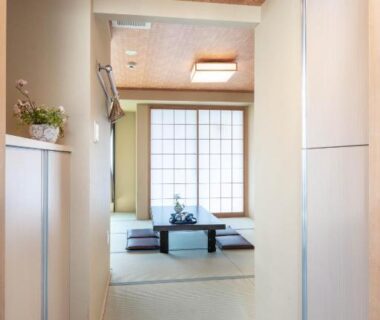 Entrance corridor opening to tatami room with low table, zabuton cushions and shoji screens at a Tokyo ryokan