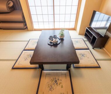 Tatami room with low table, tea set, shoji screen and television at Nihonbashi Kakigara Ryokan Tokyo