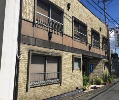 Two-story brick ryokan exterior with shuttered windows along narrow Kyoto street at Nihonkan, Kansai
