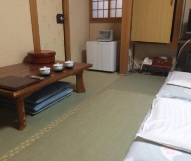 Tatami room with low wooden table, floor cushions, futons and shoji screens at Nihonkan, Kyoto, Kansai Japan
