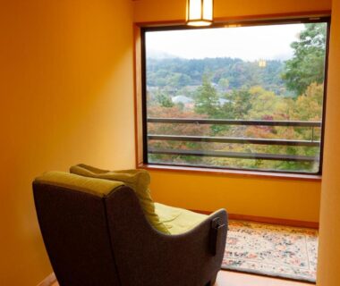 Armchair facing window with wooded hillside view at Nikko Hoshino Yado, Tochigi