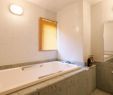 Bathroom with stone soaking tub and wall mirror at Nikko Hoshino Yado in Tochigi, Kantō, Japan