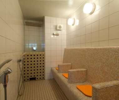 Indoor tiled bathing area with mosaic bench and shower stations at Nikko Senhime Monogatari, Tochigi