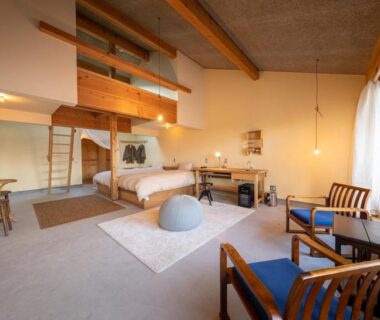 Modern guest room with bed, loft ladder, wooden beams, seating area and large window at Nisainoyuyado Asahiya in Ōita