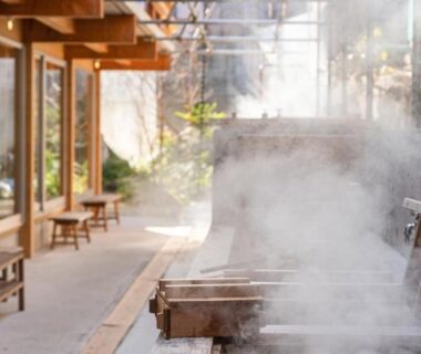 Steaming wooden baths beside a covered walkway at Nisainoyuyado Asahiya, Ōita