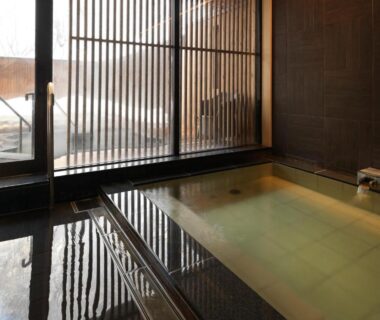 Indoor onsen bath with wooden slatted windows and tiled floor at Niseko Konbu Onsen Tsuruga Moku-no-sho Hokkaidō