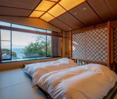 Tatami room with futon bedding and large window overlooking coastal waters near Nishiizu Koyoi, Shizuoka