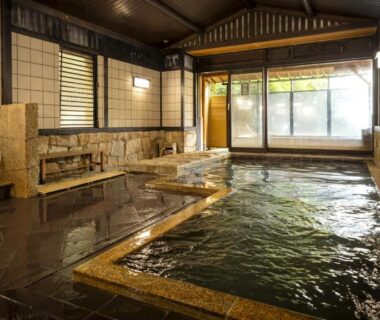 Communal indoor onsen with stone tubs, washing stations and garden-facing windows at Nishiizu Koyoi, Shizuoka