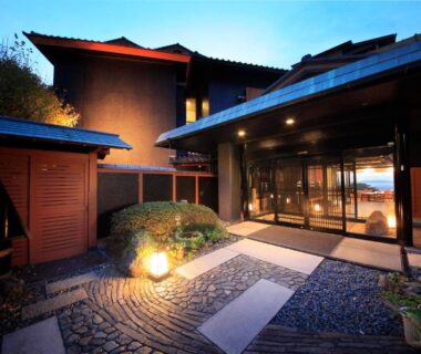 Illuminated courtyard entrance with stone path and glass doors at Nishiizu Koyoi, Shizuoka
