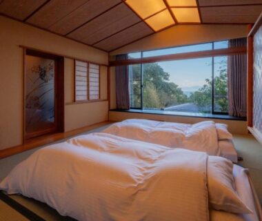Traditional tatami room with futon bedding and large window overlooking greenery at Nishiizu Koyoi, Shizuoka