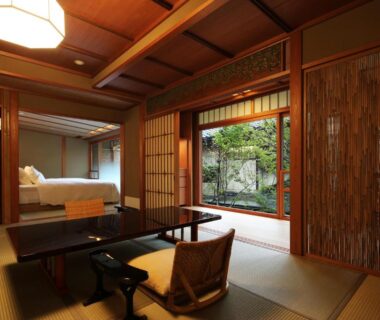 Tatami room with low table, zabuton seating, shoji screens and garden view at Nishimuraya Honkan in Hyōgo