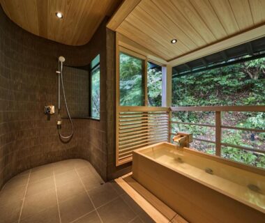 Indoor wooden soaking tub and shower overlooking lush forest from Nishimuraya Honkan in Hyōgo