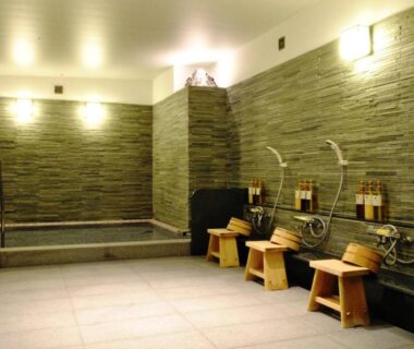 Indoor communal bath with shower stations, wooden stools and soaking pool at Nissho Besso Kyoto