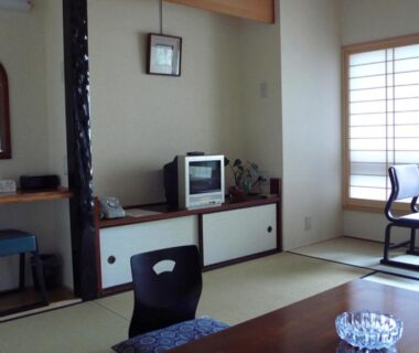 Traditional tatami room with low table, shoji screens and dressing area at Nisshokan in Mie prefecture