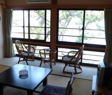 Traditional tatami room with low table, cushions and window seating at Nisshokan in Mie