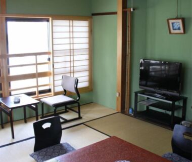Traditional tatami room with low table, shoji screens, balcony access, chairs and television in Mie, Kansai