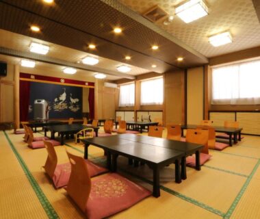 Spacious tatami dining hall with low tables, floor cushions and warm lighting at Nitaya in Gunma