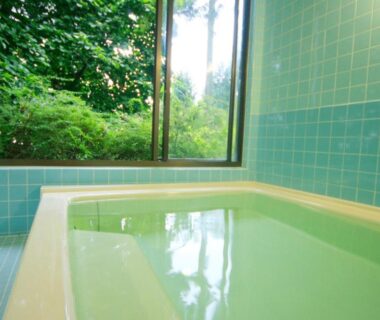Rectangular tiled soaking tub beside window overlooking lush garden foliage at Nobori in Tokyo, Kanto