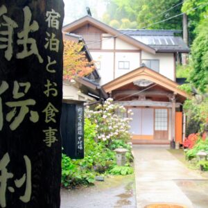 Entrance path and wooden sign at Nobori ryokan in Tokyo with lush greenery