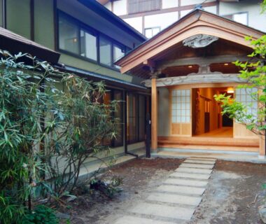 Stone path leading to Nobori ryokan wooden entrance surrounded by greenery in Tokyo, Kantō