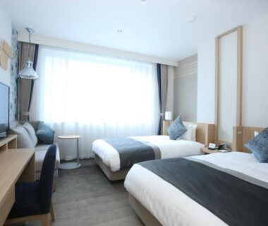 Twin beds, desk with TV, large window with sheer curtains at Noboribetsu Grand Hotel, Hokkaidō Japan