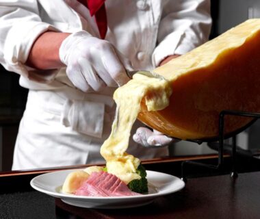 Chef scraping melted cheese onto plate at Noboribetsu Grand Hotel dining in Hokkaidō