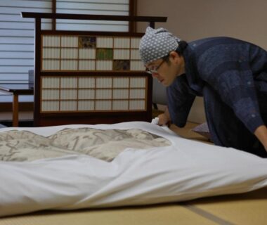 Ryokan attendant lays futon on tatami with shoji screens at Nonohanatei komurasaki, Shizuoka, Chubu Japan