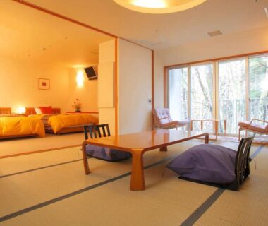 Tatami room with low table, floor cushions, twin beds and large window overlooking wooded courtyard