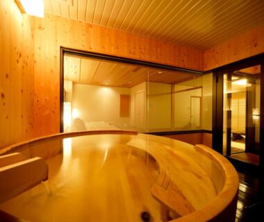 Round wooden bath in warm-lit indoor bathing room at Notoya, Ishikawa, Chūbu, Japan