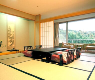 Traditional tatami room with low dining table, floor cushions, shoji screens and greenery view at Notoya in Ishikawa