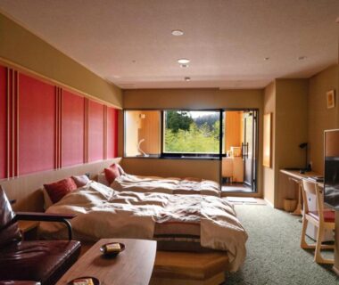 Room with futon bedding, low table, seating and window view of trees at Notoya, Ishikawa, Chūbu