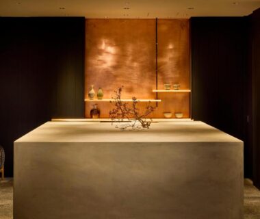 Stone reception counter with wooden backdrop and branch arrangement at ONCRI-Karatsu in Saga, Kyūshū