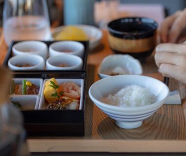 Bowl of steamed rice with assorted small side dishes on wooden tray in ryokan dining setting