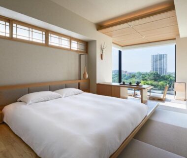Low bed with tatami seating, shoji screens and large window overlooking urban greenery at ONSEN RYOKAN Yuen Sapporo, Hokkaidō