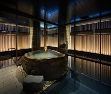 Indoor stone onsen bath with wooden panels and soft lighting at ONSEN RYOKAN Yuen Sapporo, Hokkaidō